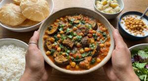 Woman holding a bowl of Gingered Chickpeas with Eggplant, Spinach and Tomato (Kabli Chana Baigan Tarkari).