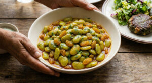 Bowl of Sem Kishmish Foogath made with fresh lima beans, golden raisins, and coriander.